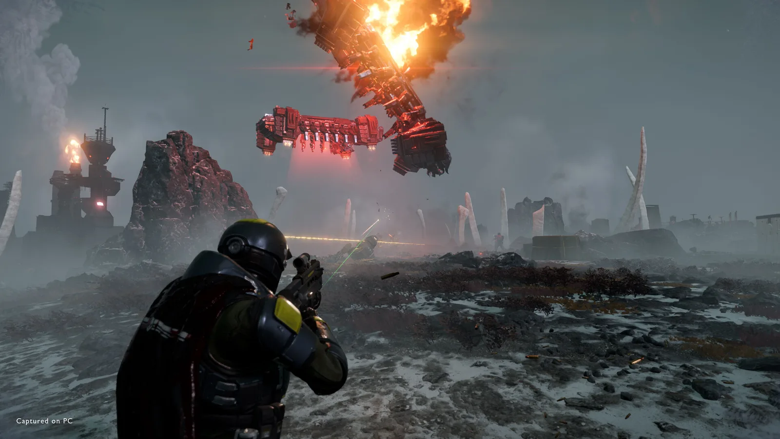 Кадр из Helldivers 2: десантник целится, над каменистой равниной висят два корабля, один охвачен огнём